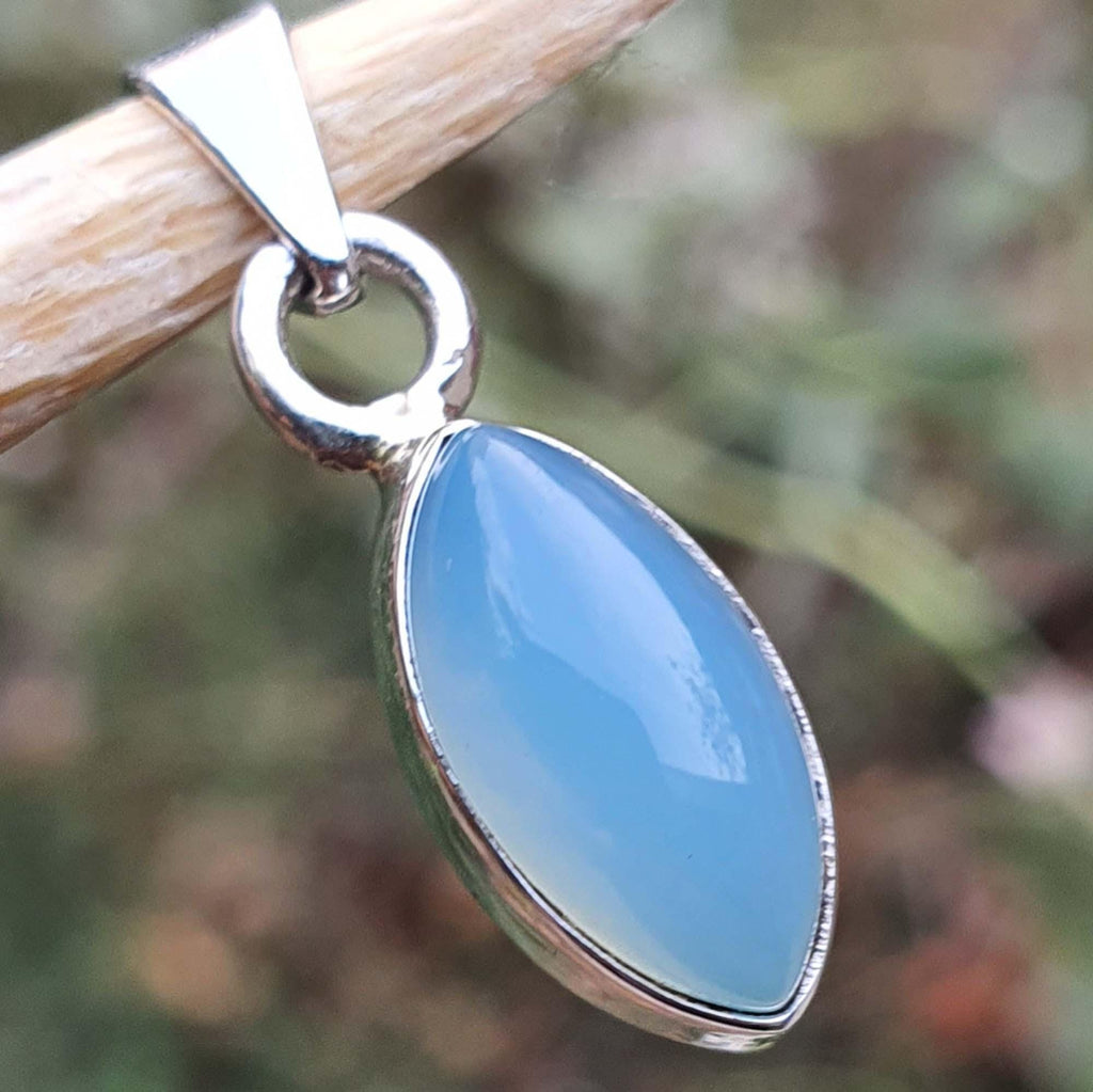 Blue pendant with silver frame on a blurred natural background