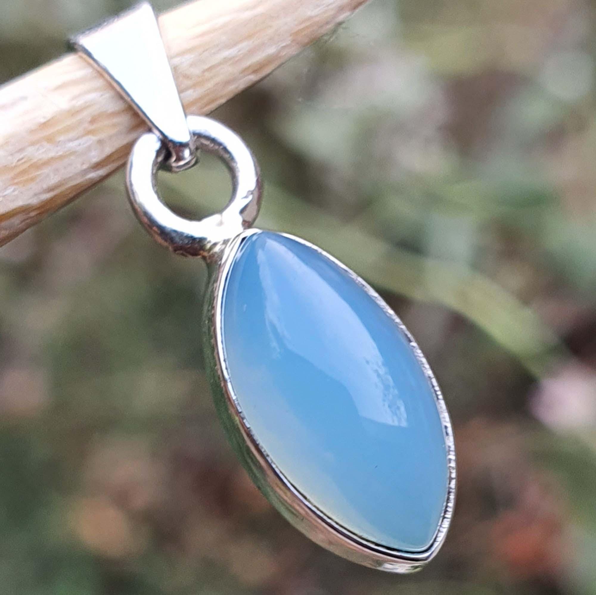 Blue pendant with silver frame on a blurred natural background