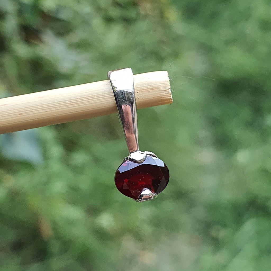 Garnet pendant on a stick with a blurred green background