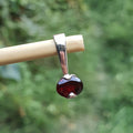 Garnet pendant on a stick with a blurred green background