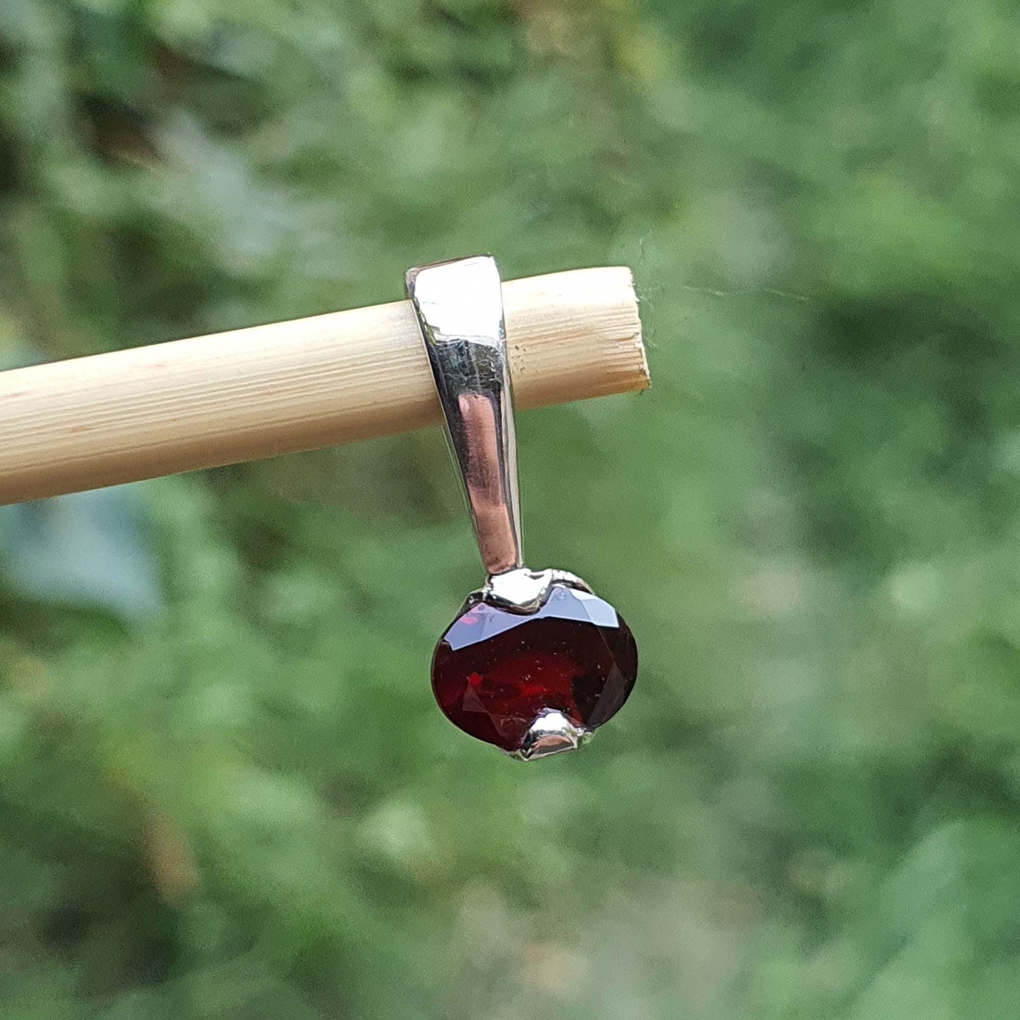 Garnet pendant on a stick with a blurred green background