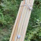 Silver necklace with a heart pendant on a wooden stick against a green leafy background