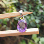 Purple gemstone pendant on a stick with a blurred green background