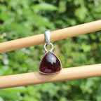 Garnet pendant on silver chain against a natural green background