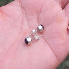 Silver earrings with purple stones held in a hand