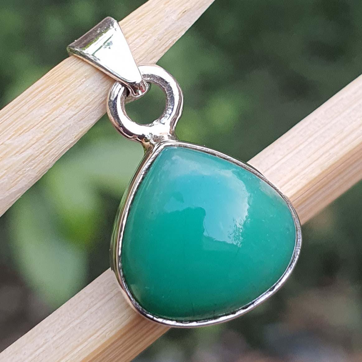 Green teardrop pendant with silver setting on a wooden stick