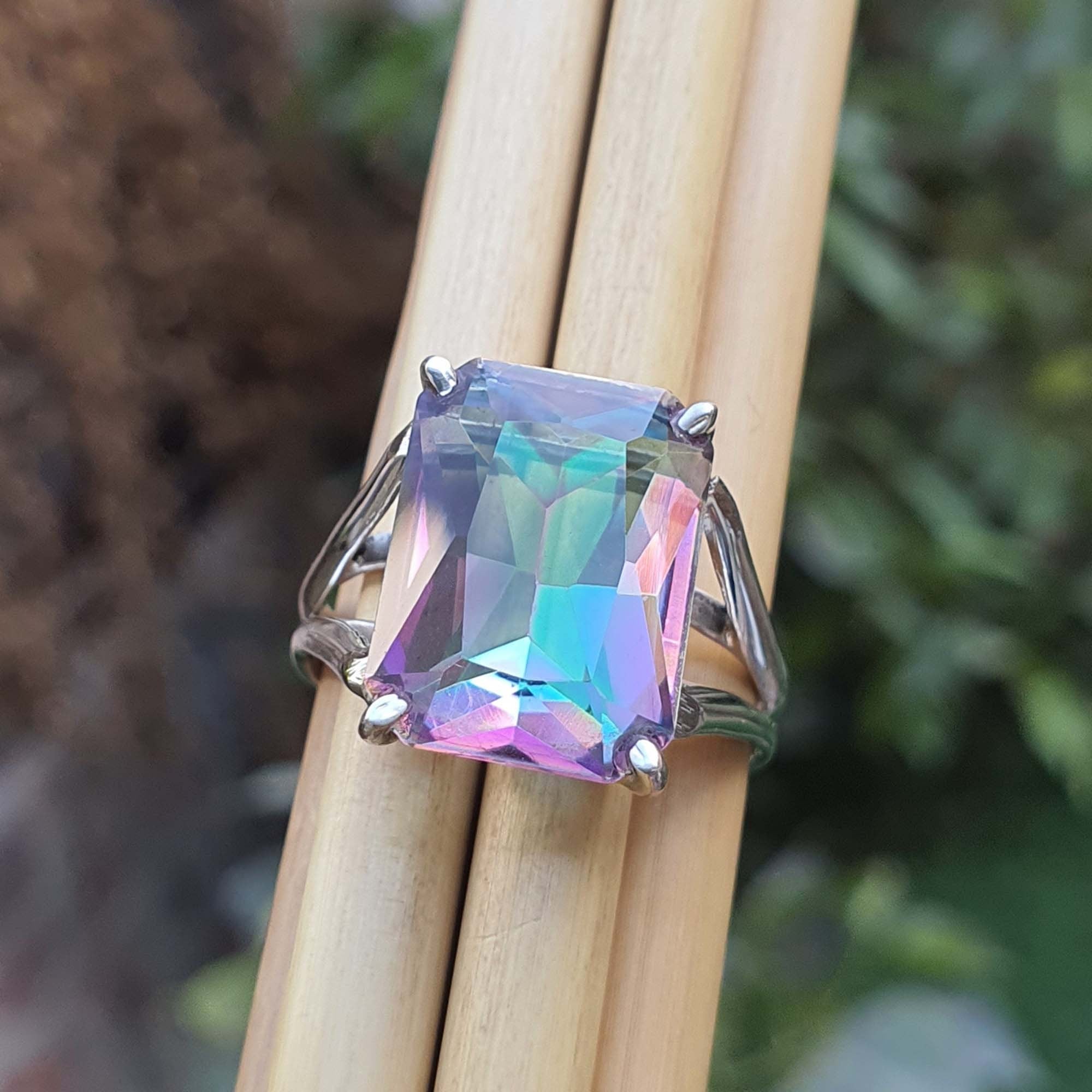Multicolored gemstone ring on a wooden stick with a blurred natural background