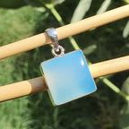 Blue square pendant on a silver chain against a green leafy background