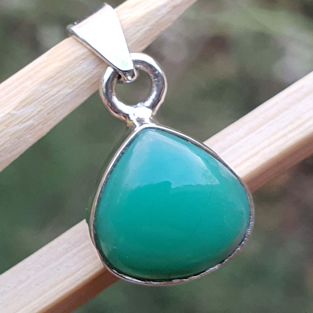 Teal pendant with silver setting on a wooden stick