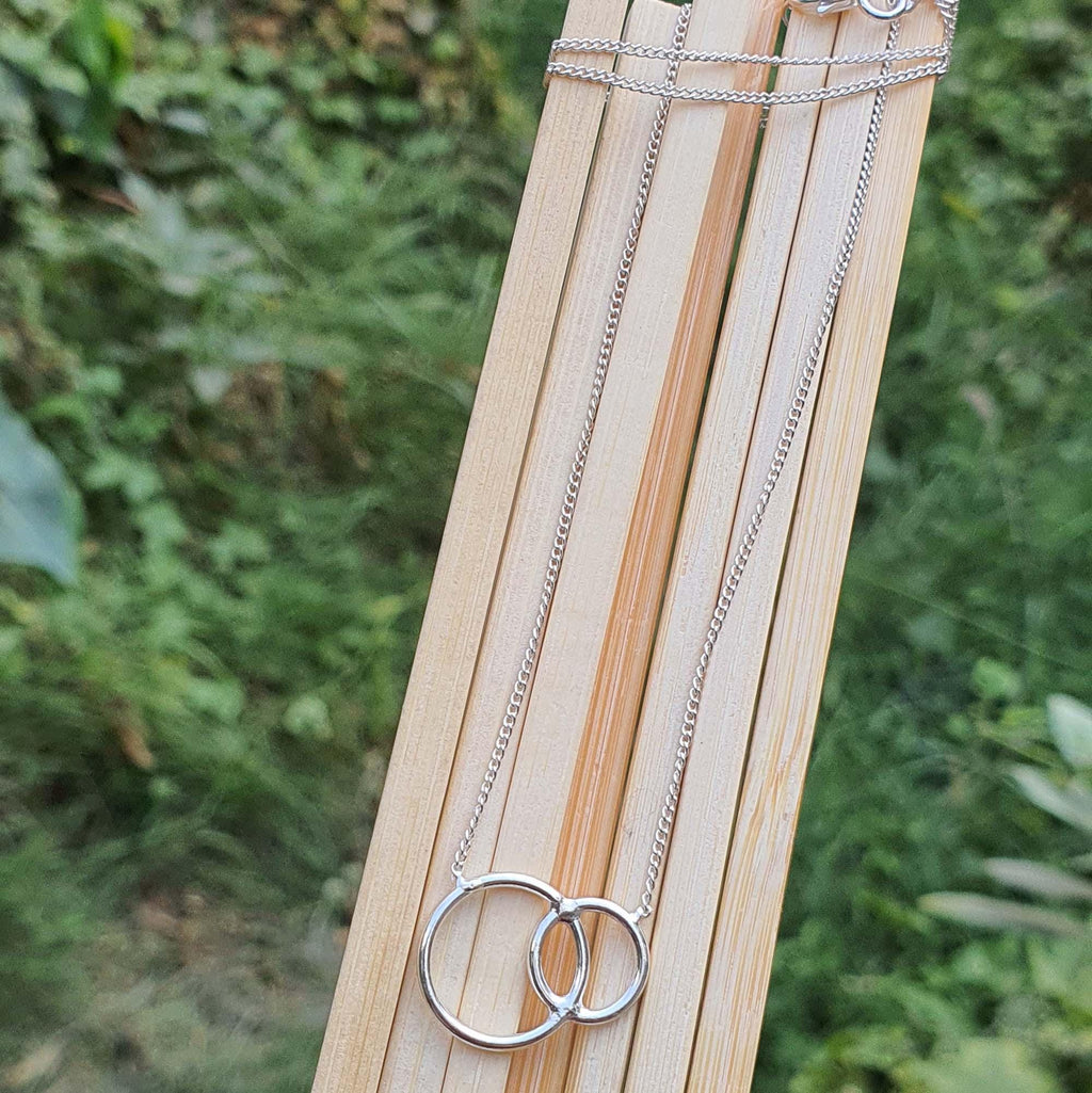 Silver necklaces on a wooden stick with a natural background
