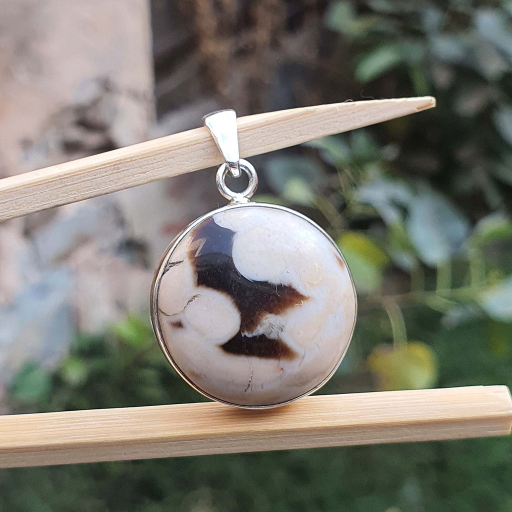 Round stone pendant on a wooden stick with a natural background