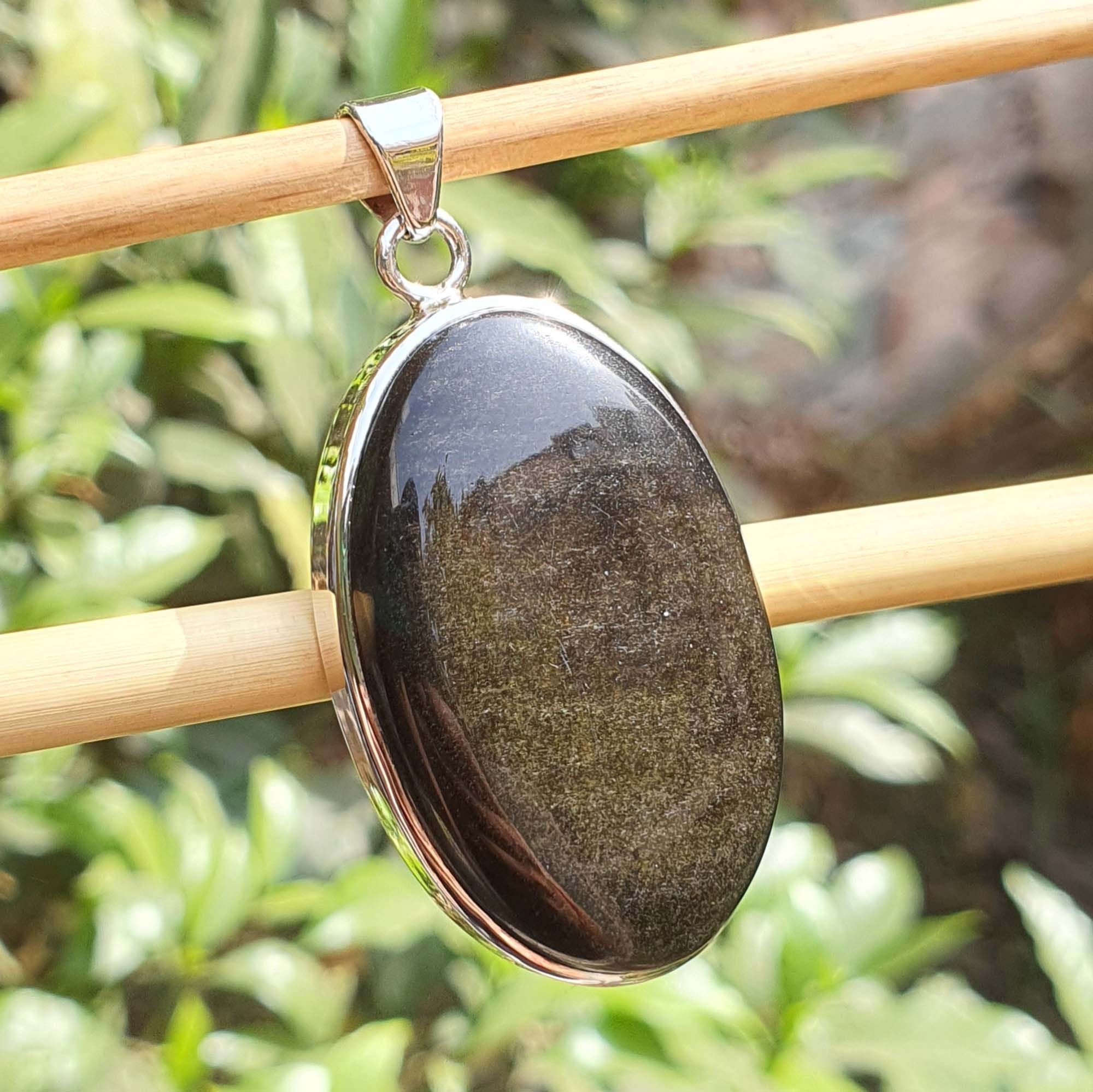Black stone pendant on a wooden stick with a blurred green background