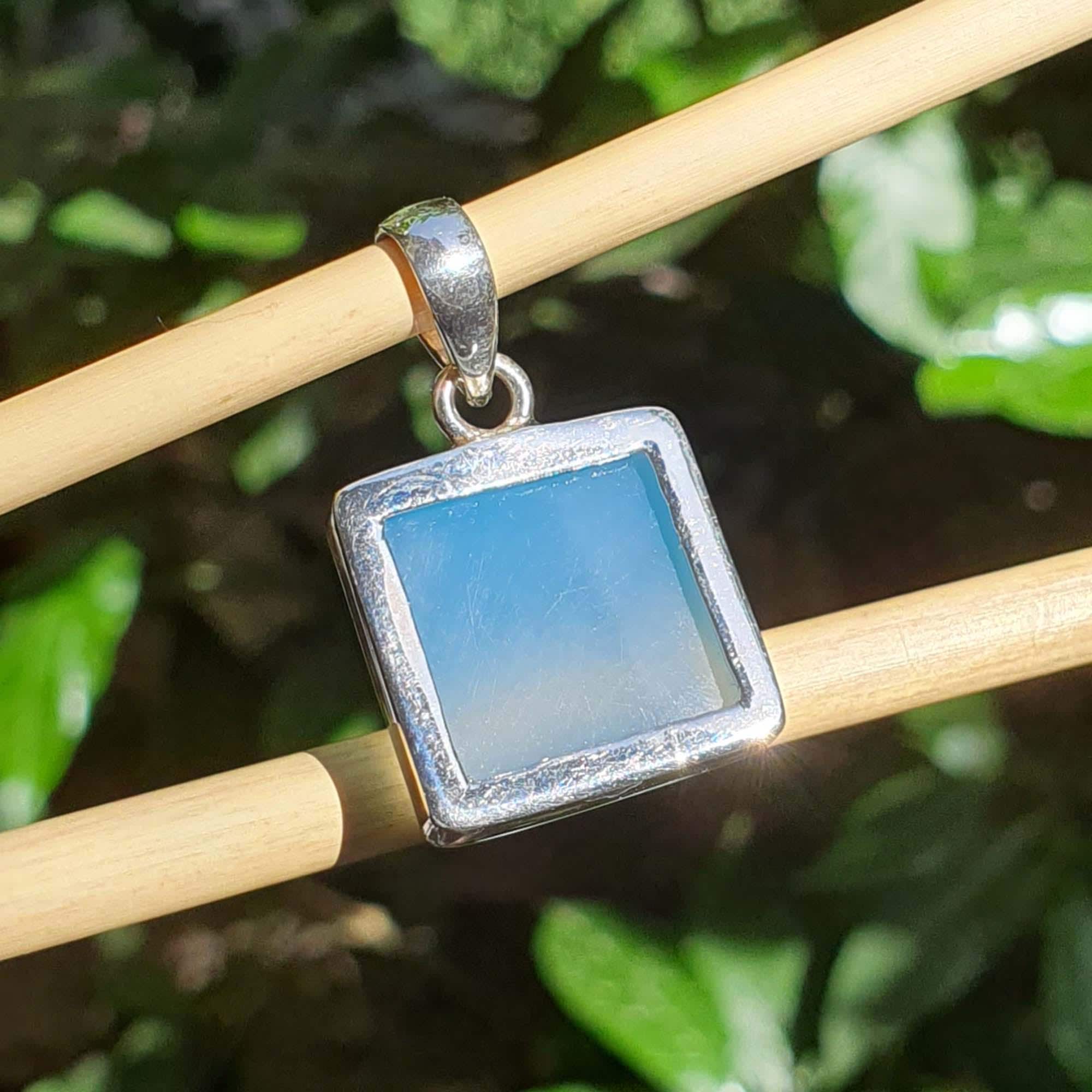 Blue stone pendant on a silver chain against a natural background