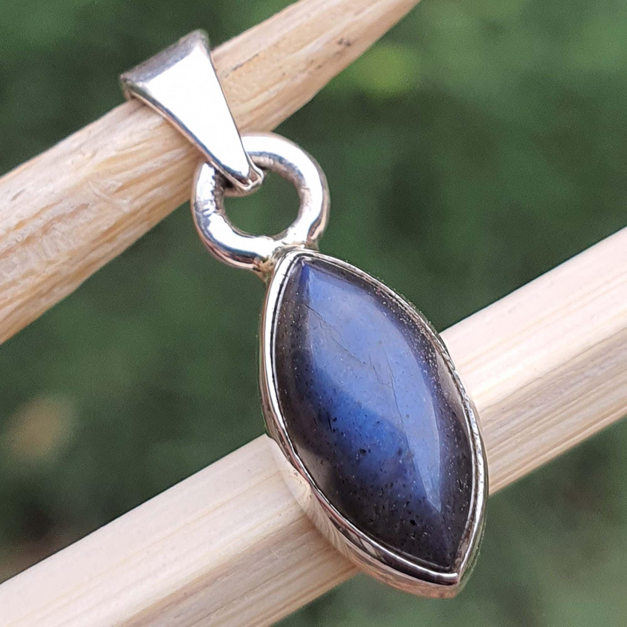 Silver pendant with a blue stone on a wooden stick