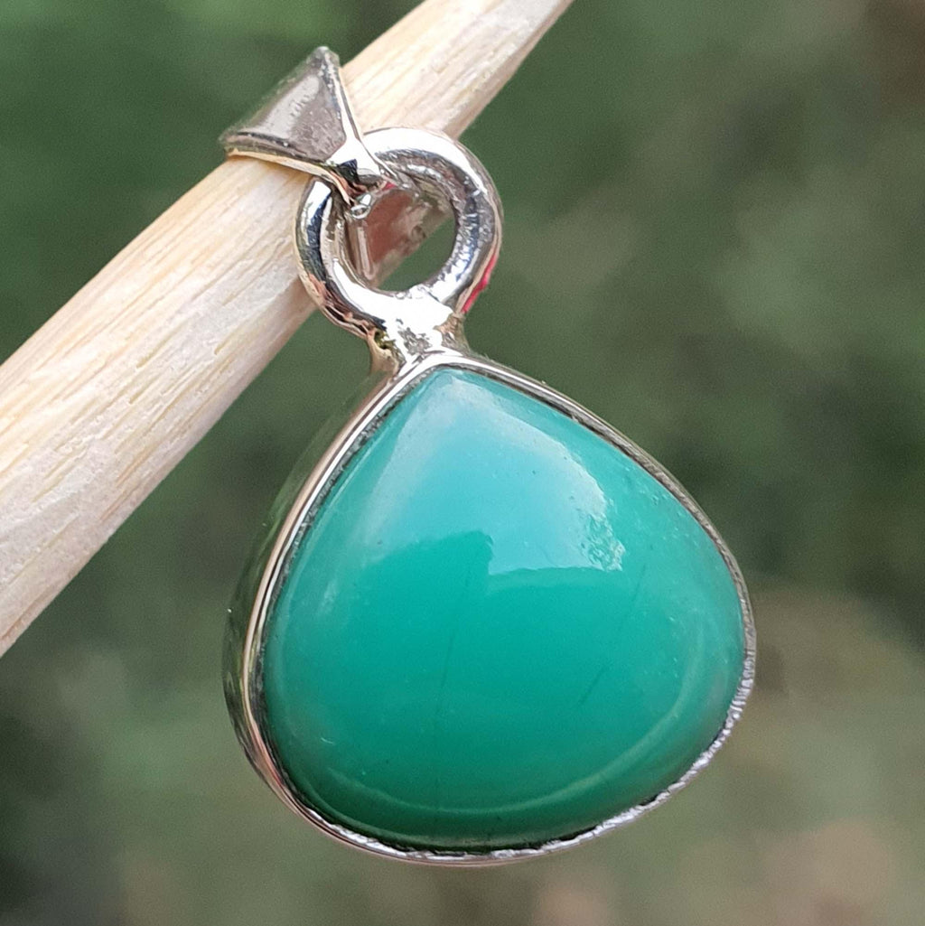 Green teardrop pendant with silver setting on a blurred green background