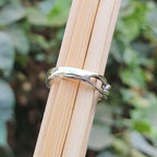 Silver ring on a wooden stick with a blurred green background
