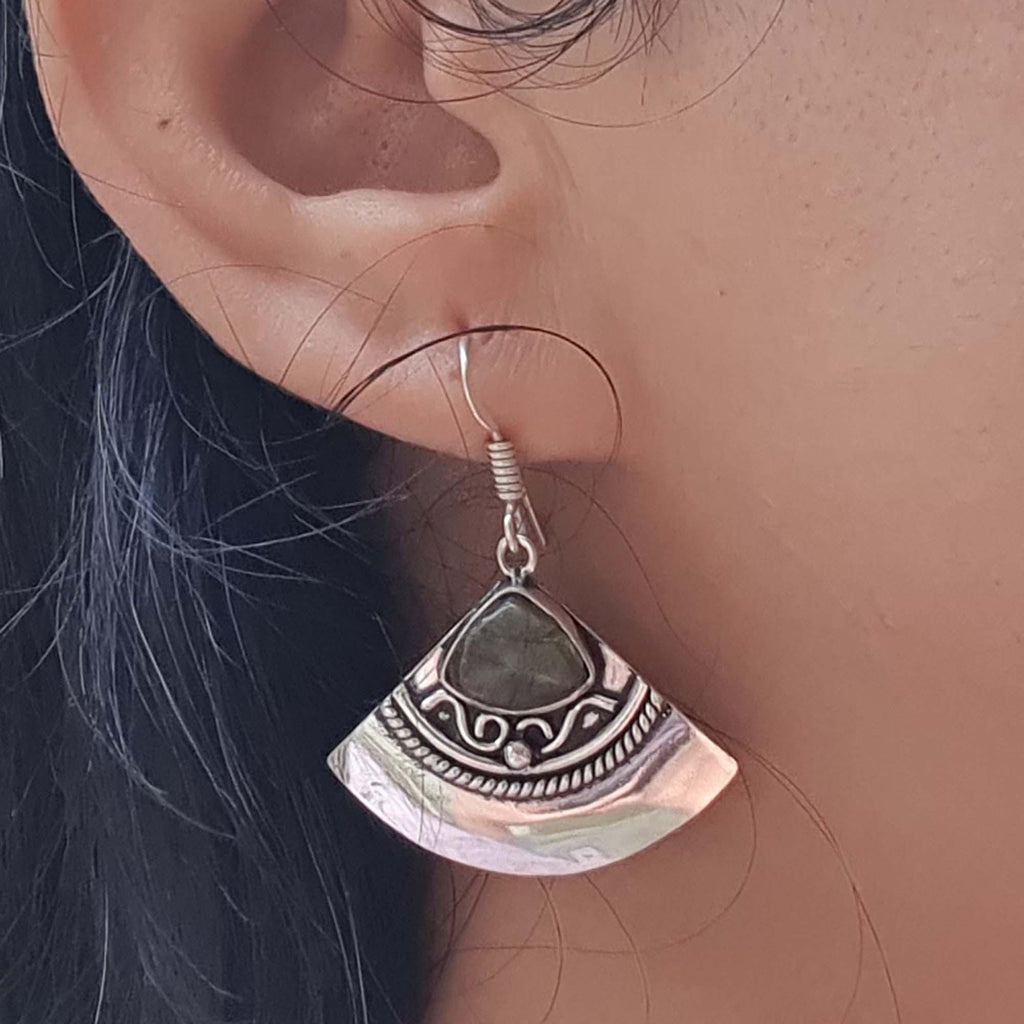 Silver earring with green stone worn by a person