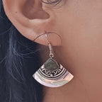 Silver earring with green stone worn by a person