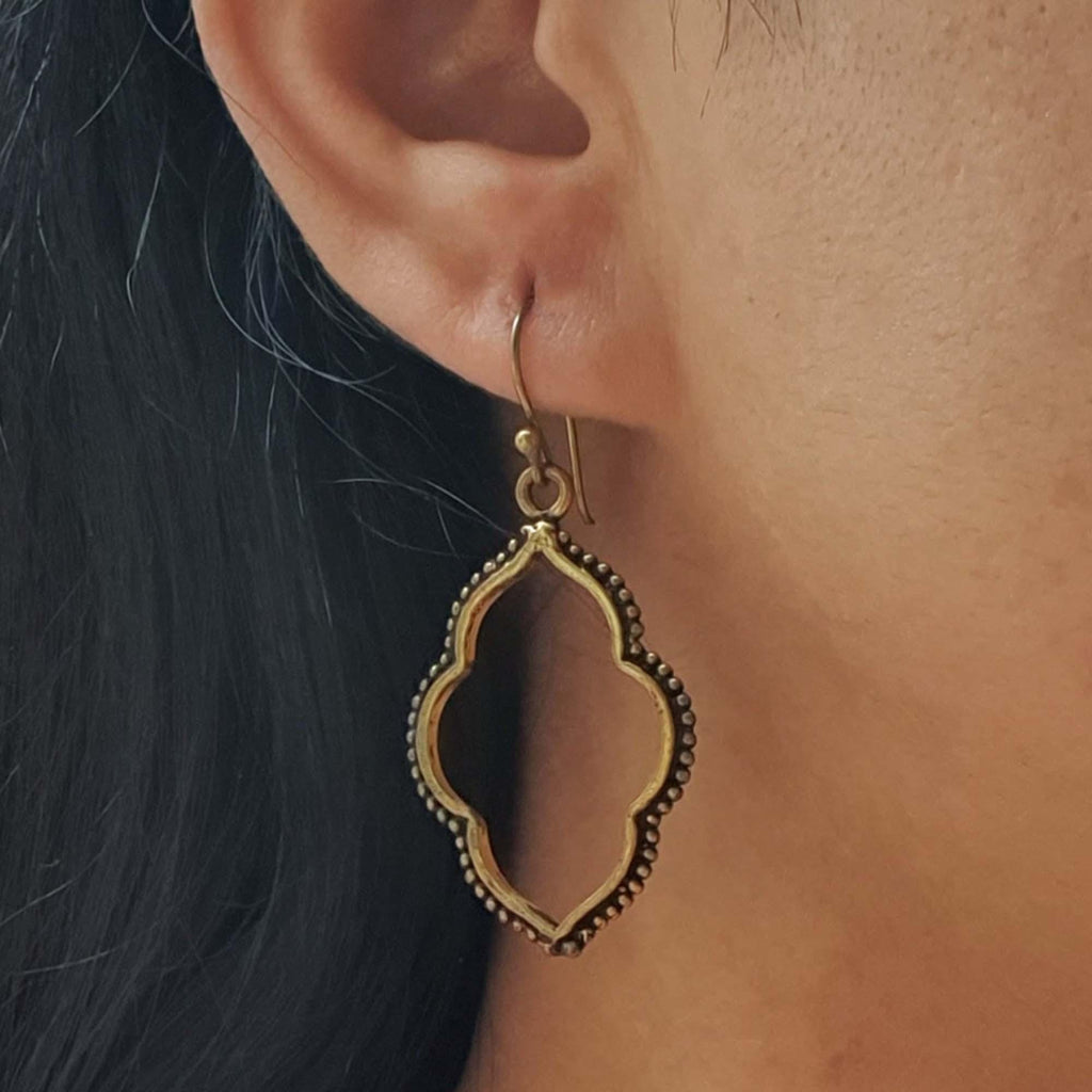 Gold earrings worn by a person with dark hair.
