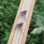 Purple gemstone earrings on a wooden stick with a natural background