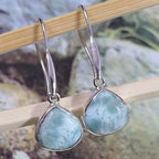Silver earrings with light blue stones on a wooden stick