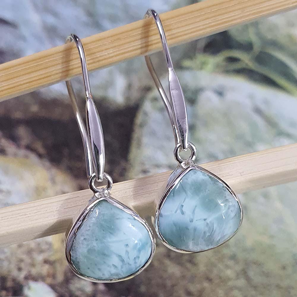 Silver earrings with light blue stones on a wooden stick