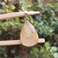 Teardrop-shaped pendant on a stick with a blurred green background