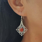 Silver earring with a red gemstone worn by a person