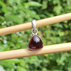Garnet pendant on silver chain against a natural green background