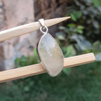 Teardrop-shaped pendant on a wooden stick with a blurred green background