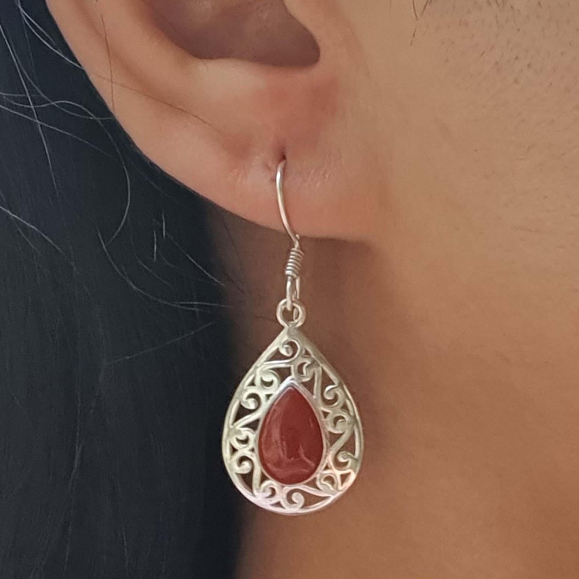 Silver earring with a red stone worn by a person