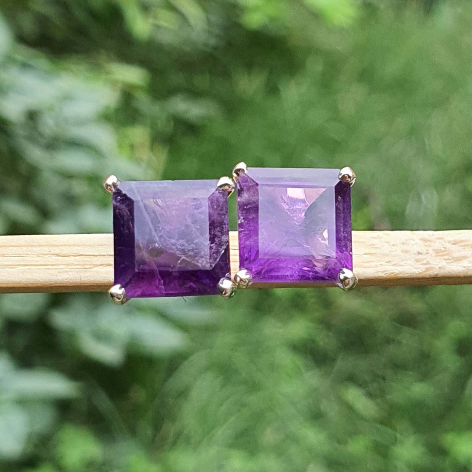 Amethyst earrings on a stick with a blurred green background