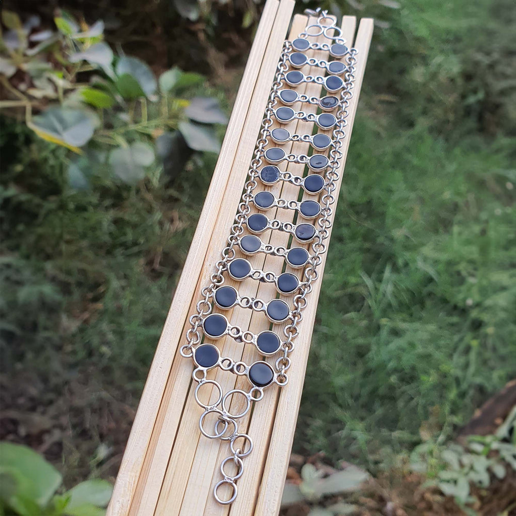 Necklace with blue and silver circular pendants on a wooden stick against a natural background