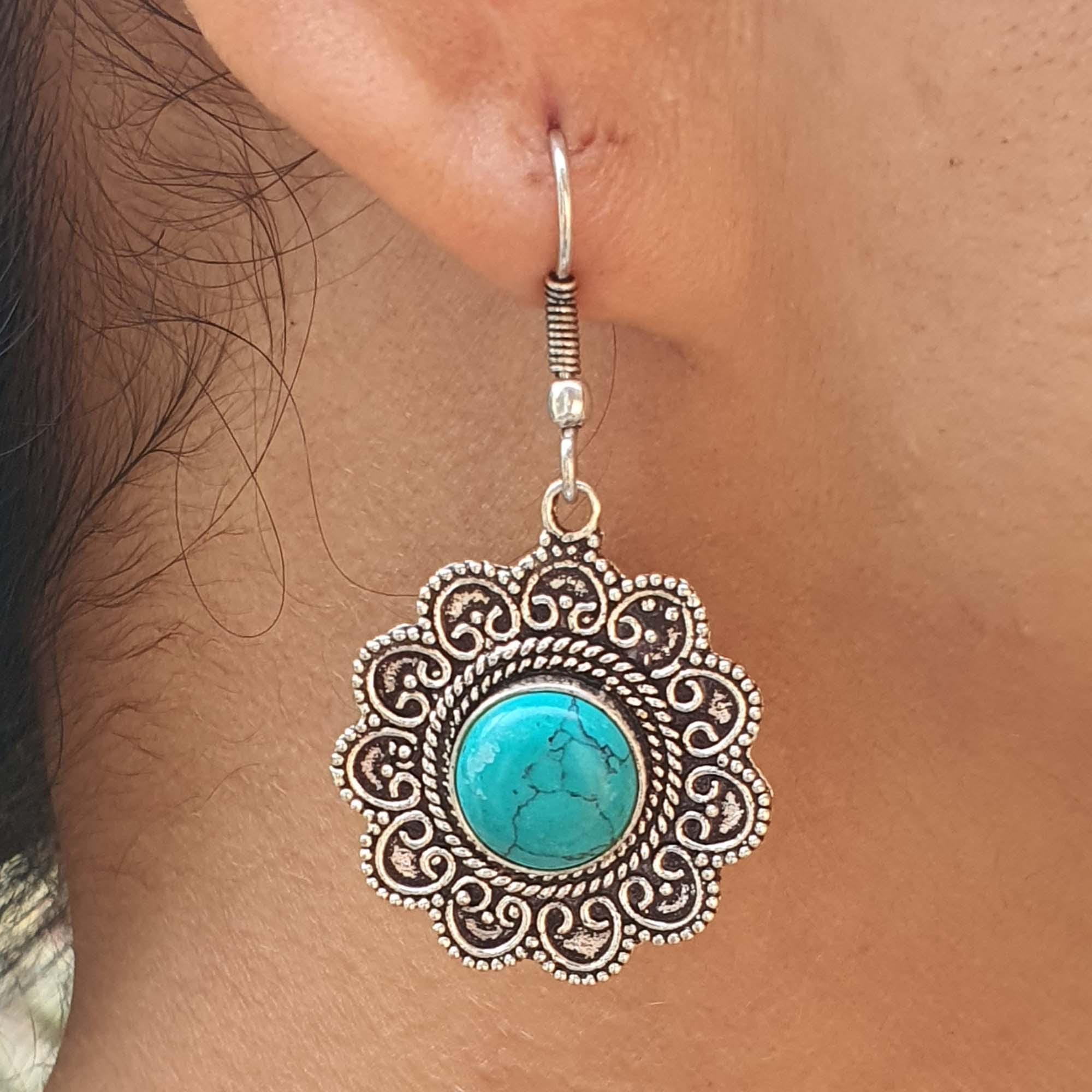 Silver earring with turquoise stone worn on an ear