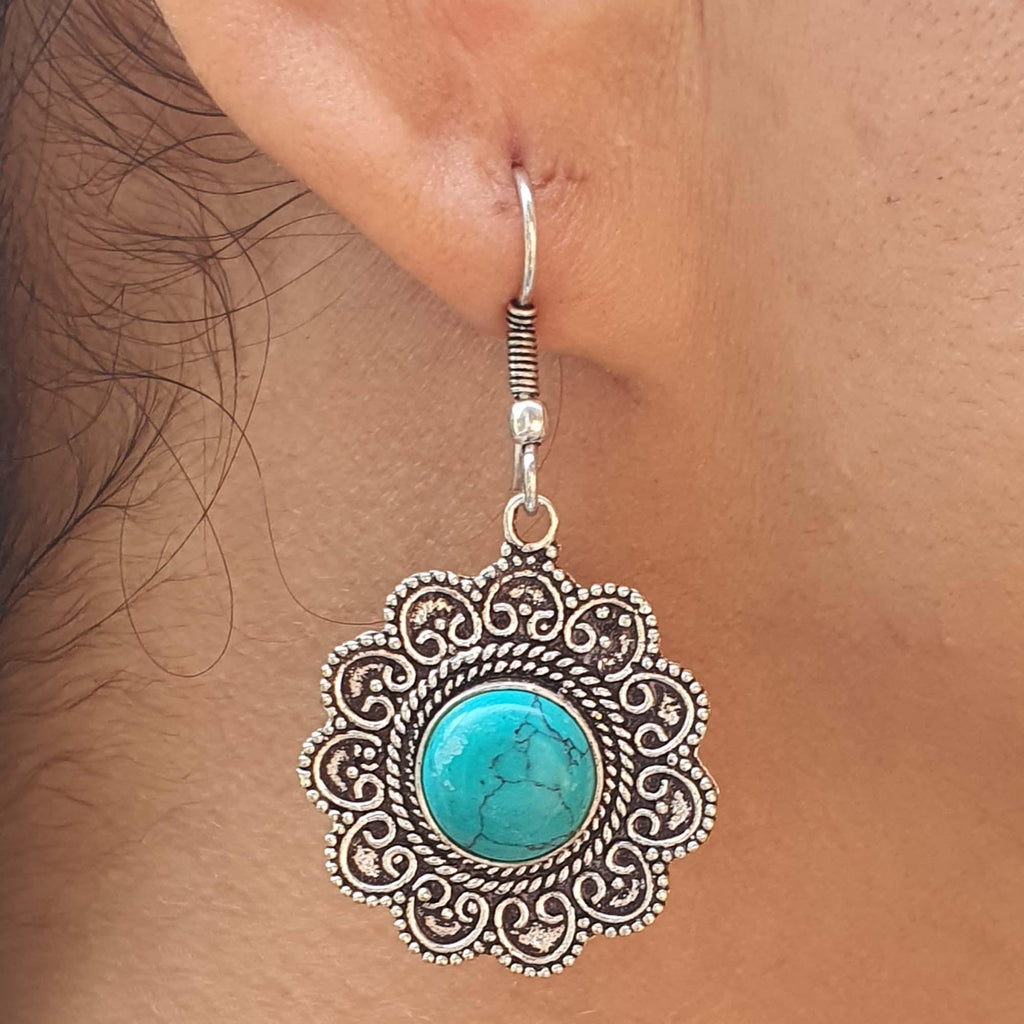 Silver earring with turquoise stone worn on an ear