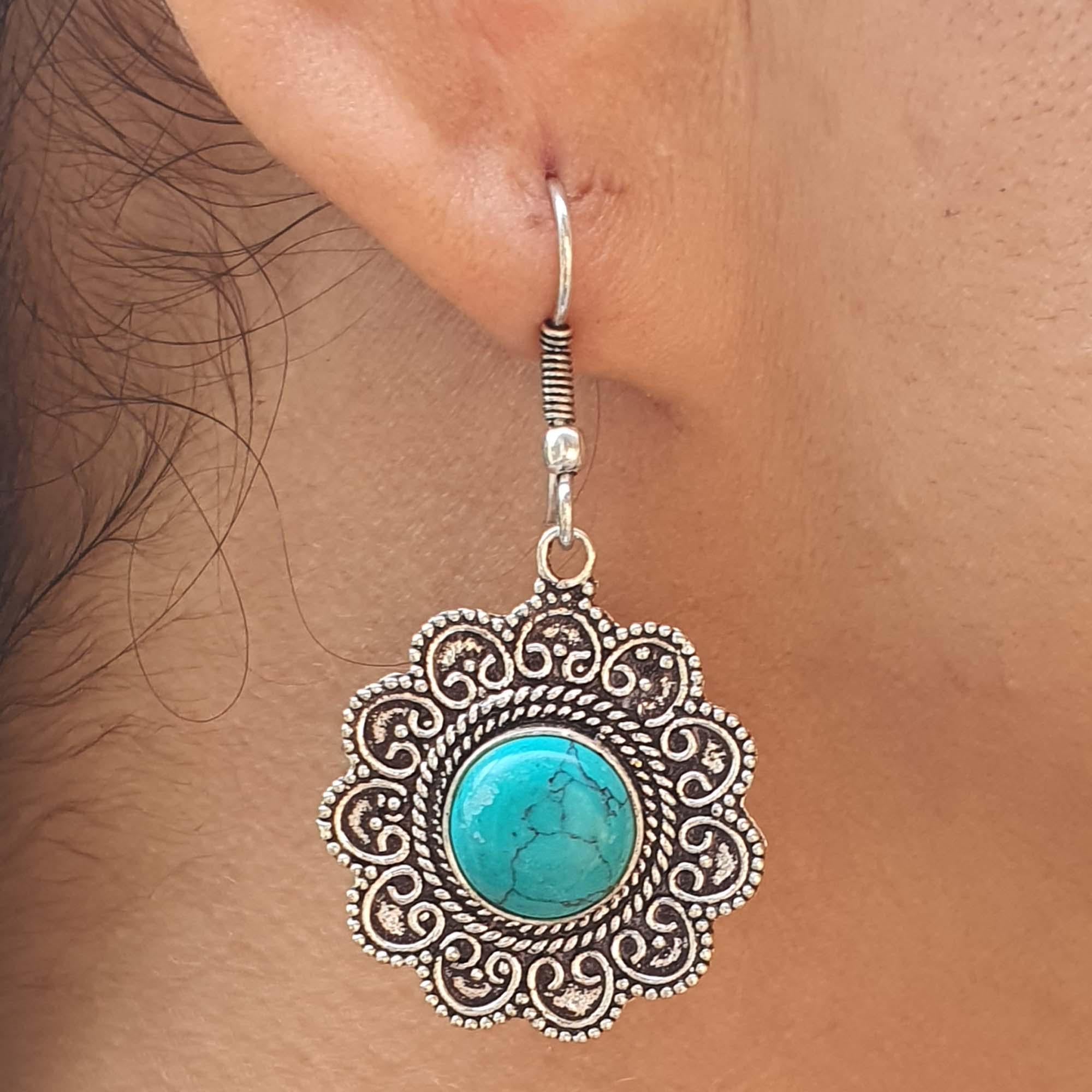 Silver earring with turquoise stone worn on an ear