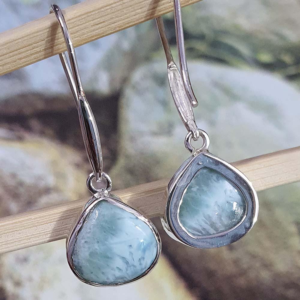 Silver earrings with teal stones on a wooden stick