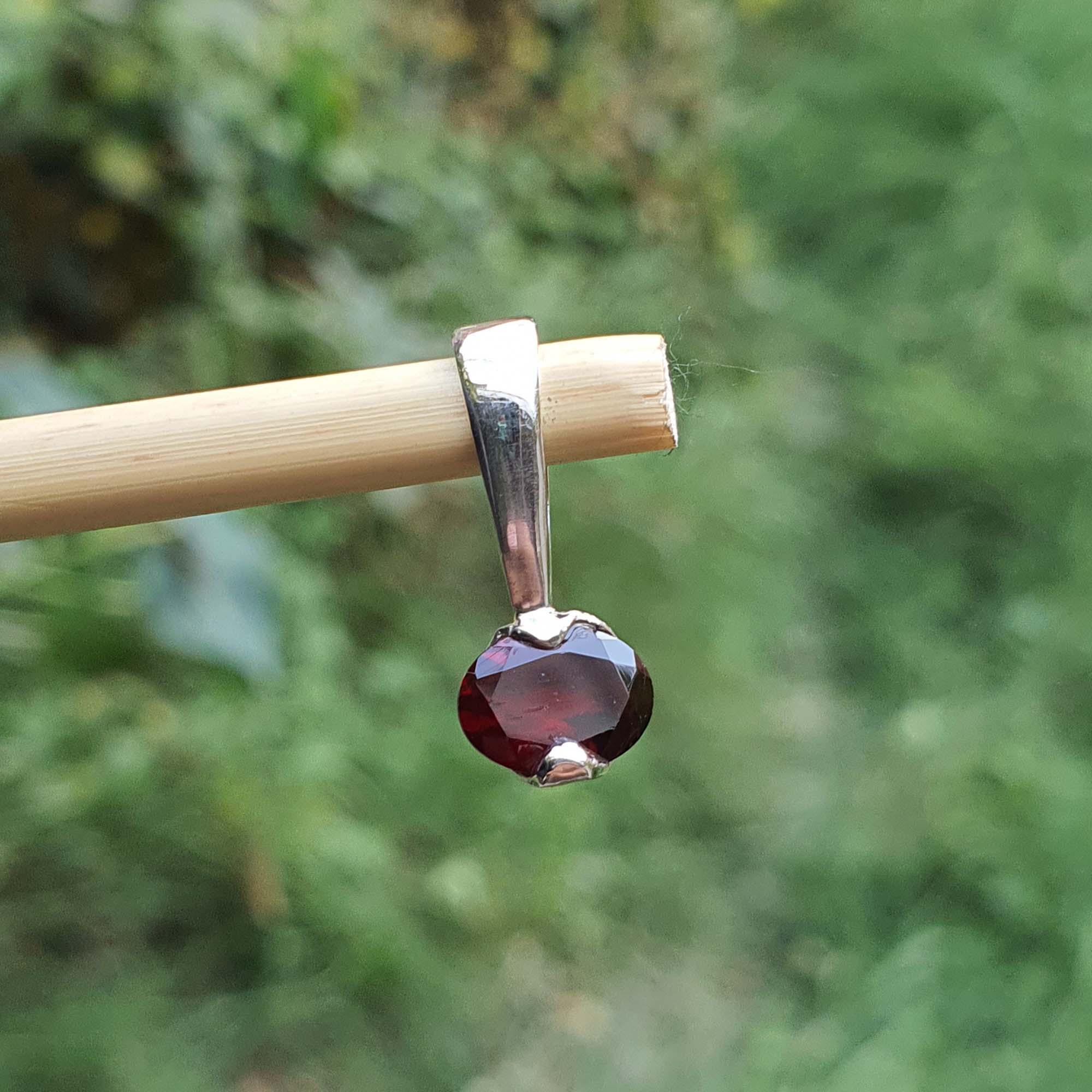Garnet pendant on a stick with a blurred green background