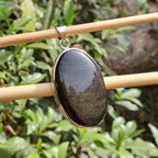 Black stone pendant on a wooden stick with a natural background