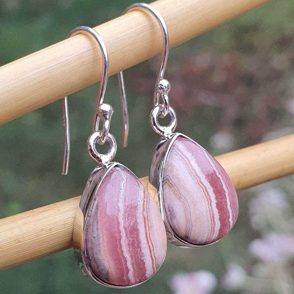 Pink stone earrings on a wooden stick with a blurred natural background