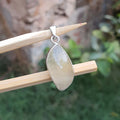 Teardrop-shaped pendant on a stick with a blurred natural background