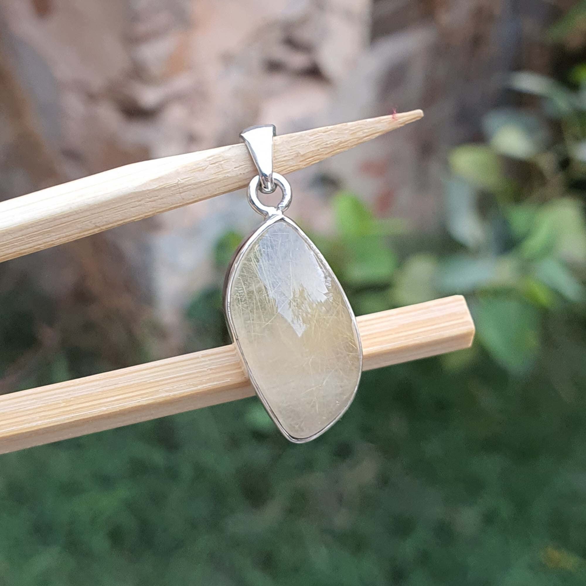 Teardrop-shaped pendant on a stick with a blurred natural background