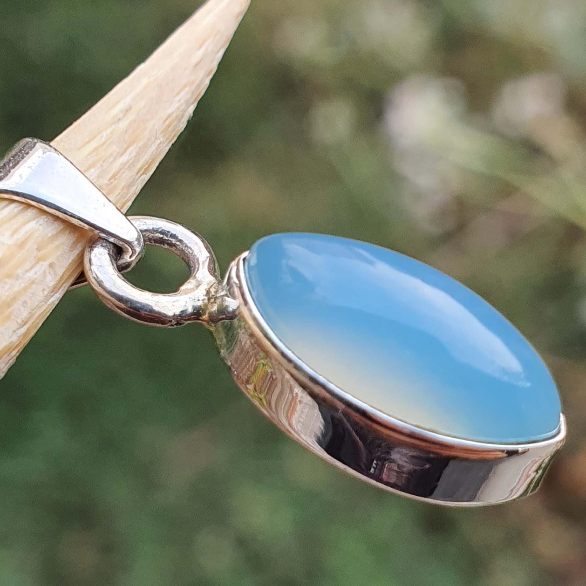 Blue pendant with silver setting on a blurred natural background