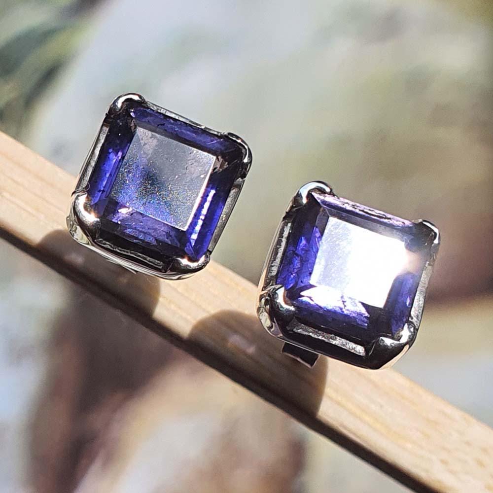 Pair of square-cut purple gemstone earrings on a wooden surface with a blurred natural background.