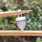 Pendant with a rainbow moonstone on a wooden stick against a blurred green background