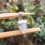 Tribal-style pendant with a stone on a wooden stick against a blurred green background