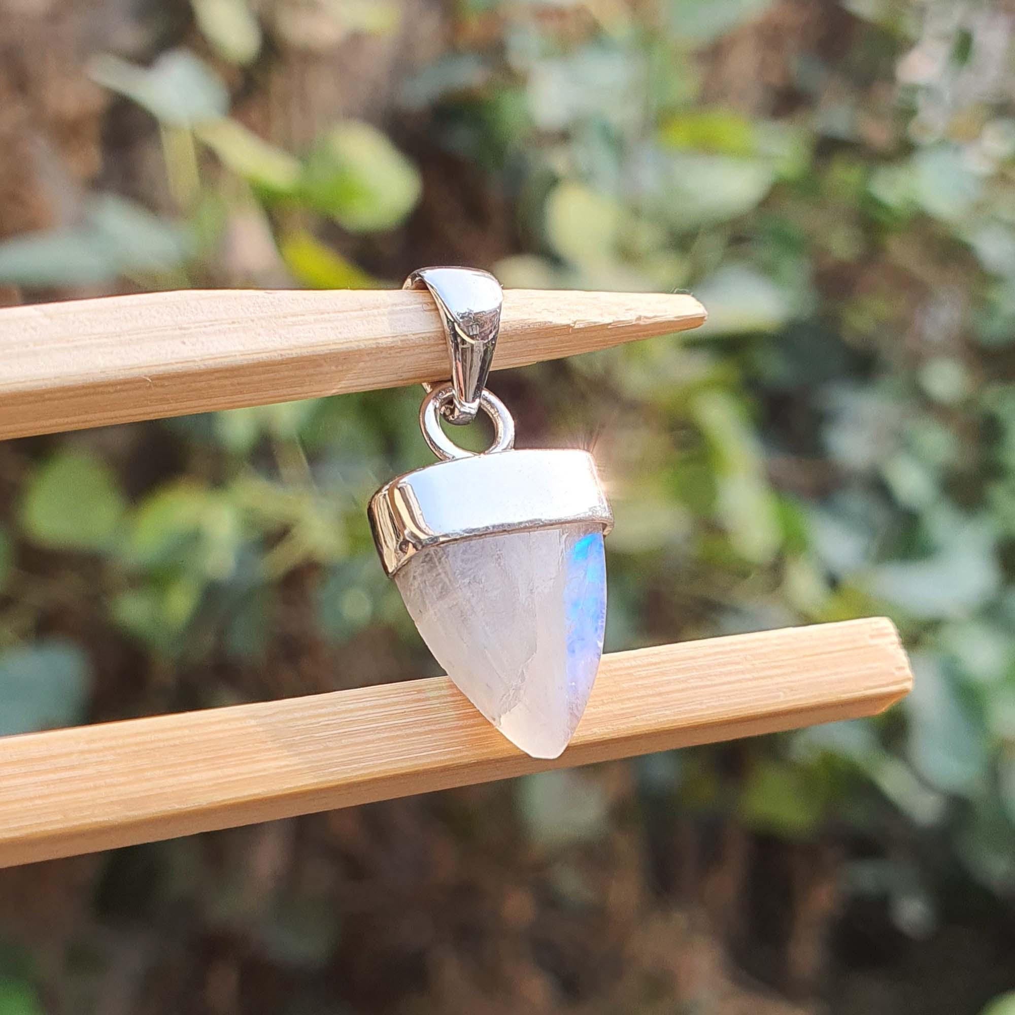 Tribal-style pendant with a stone on a wooden stick against a blurred green background